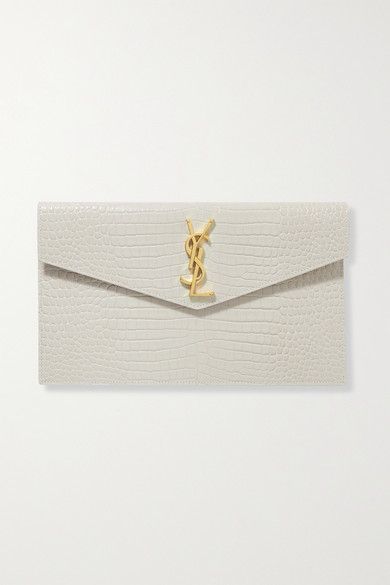 SAINT LAURENT's 'Uptown' pouch fits everything you need for an evening at a gallery opening or rooftop bar. It's been made in Italy from croc-effect leather and decorated with the iconic 'YSL' hardware in gold. Carry it in hand or slip it inside one of the brand's bags. -- Off-white croc-effect leather (Calf) - Magnetic-fastening front flap - Designer color: Blanc Vintage - Made in Italy Ysl Crocodile Bag White, Ysl Clutch, Gallery Opening, Accessories Bags Shoes, Yves Saint Laurent Bags, Croc Leather, Luxury Purses, Crystal Beads Bracelet, Rooftop Bar