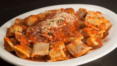 pasta with sauce and parmesan cheese in a white bowl on a black table