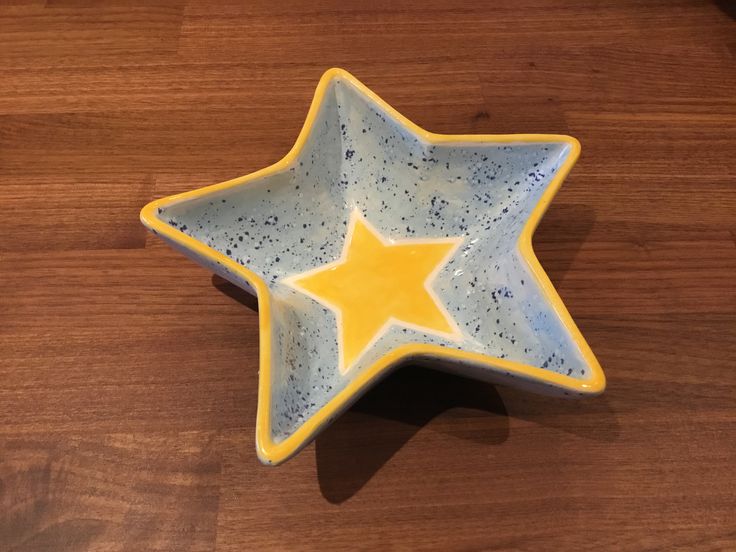 a yellow and white ceramic star dish on a wooden table