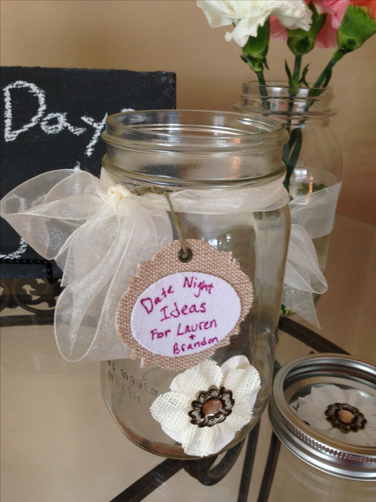 a jar with some flowers in it on a table next to a chalkboard sign