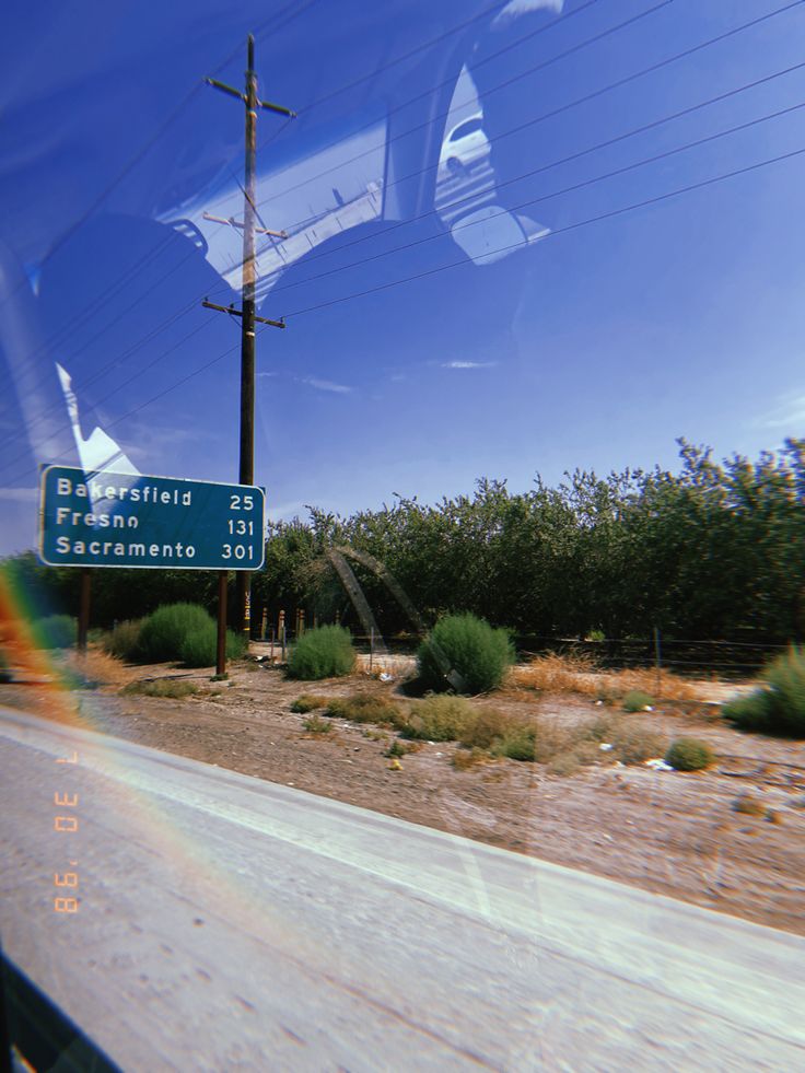 a street sign sitting on the side of a road next to a forest and telephone pole