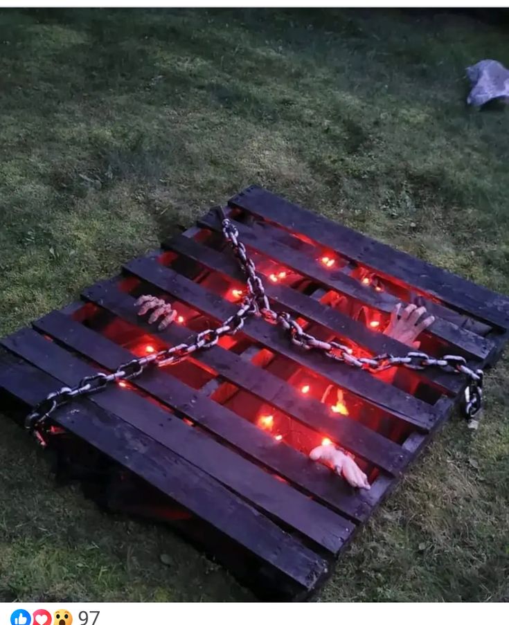 a wooden pallet with chains attached to it and lights on the ground in front of it