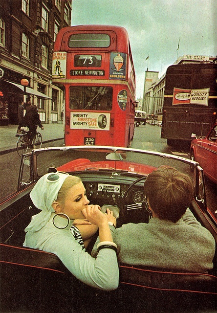 two people sitting in the driver's seat of a car on a city street