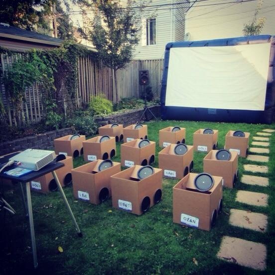 an outdoor movie is set up in the yard with cardboard boxes around it and a projector screen