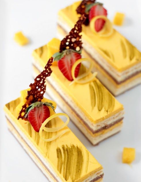 three pieces of cake with strawberries on top and yellow icing around the edges