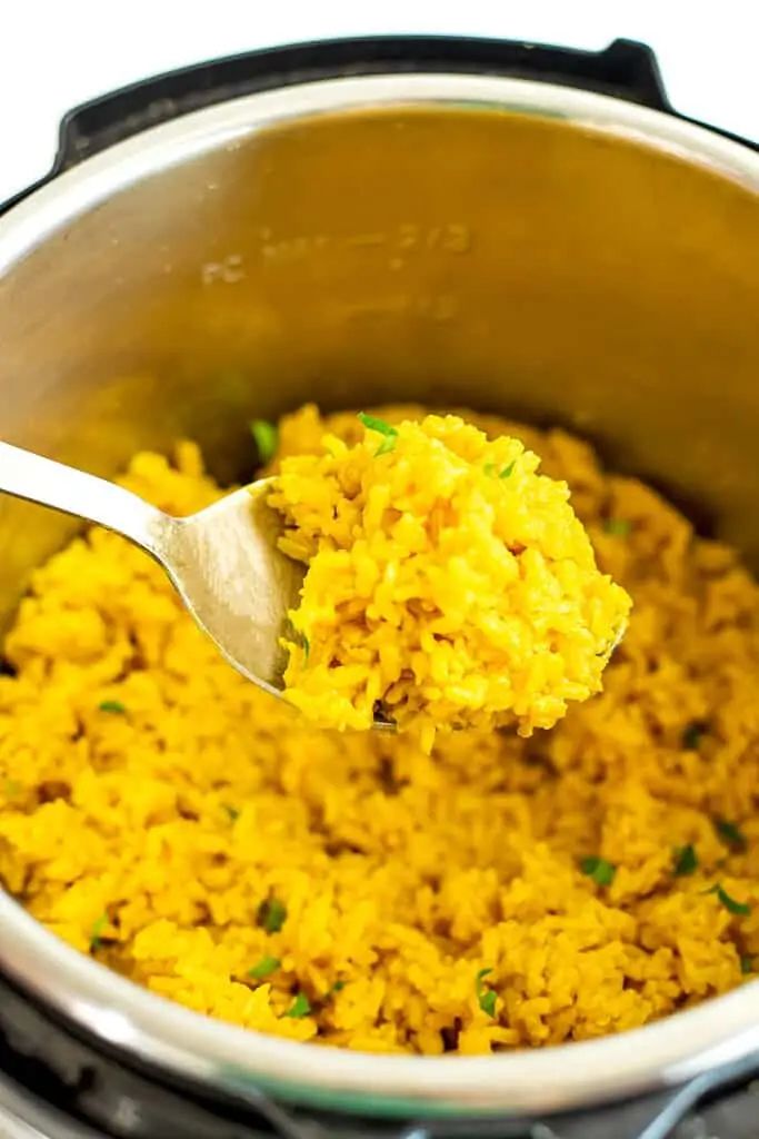 a spoon full of yellow rice in an instant pressure cooker with the lid open