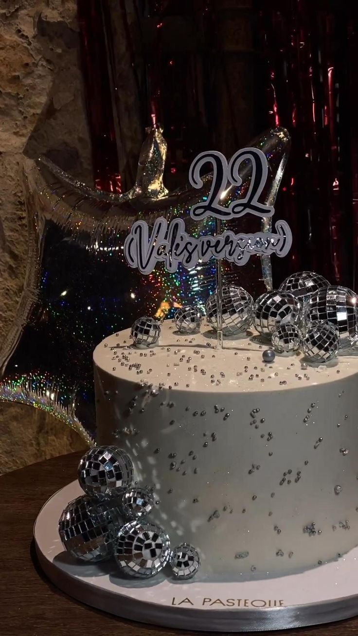 a white cake with silver frosting and decorations on top is sitting on a table