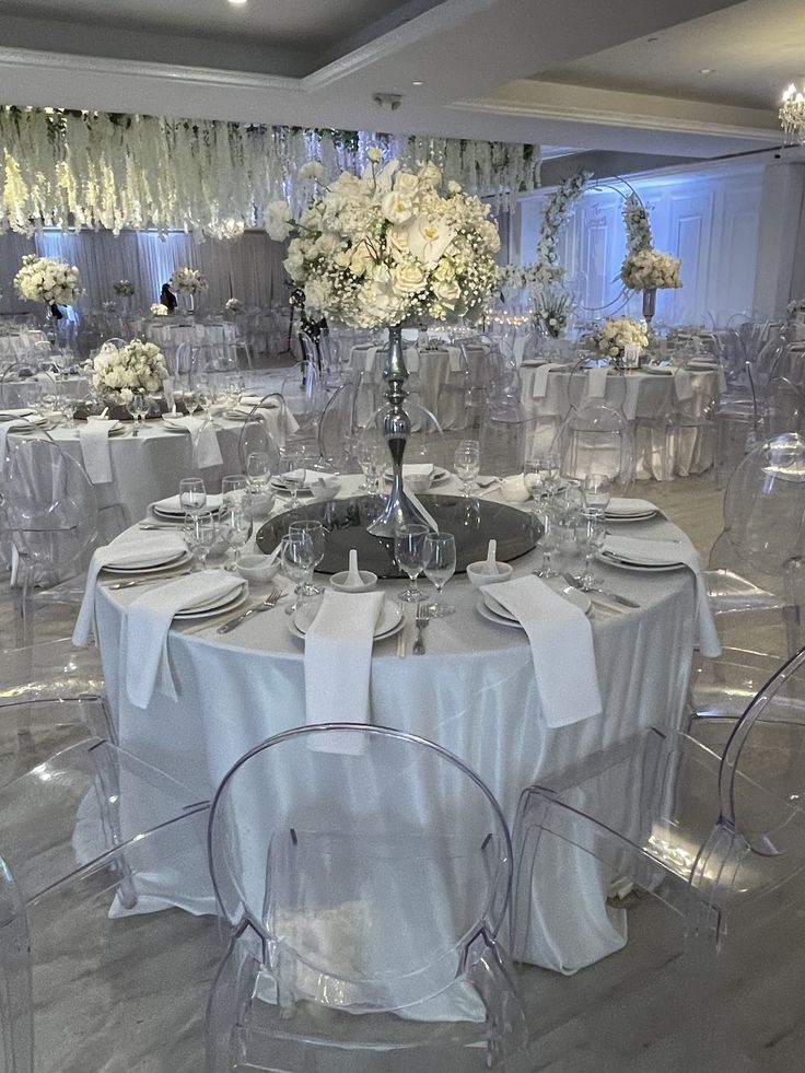 a room filled with lots of tables covered in white cloths and chairs next to each other