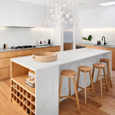 a kitchen with white counter tops and wooden stools next to an island in the middle