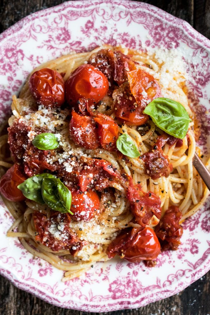 a plate of spaghetti with tomatoes, basil and parmesan cheese