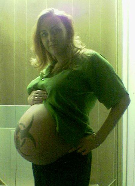 a pregnant woman standing in front of a bathroom mirror with her belly wrapped around her waist