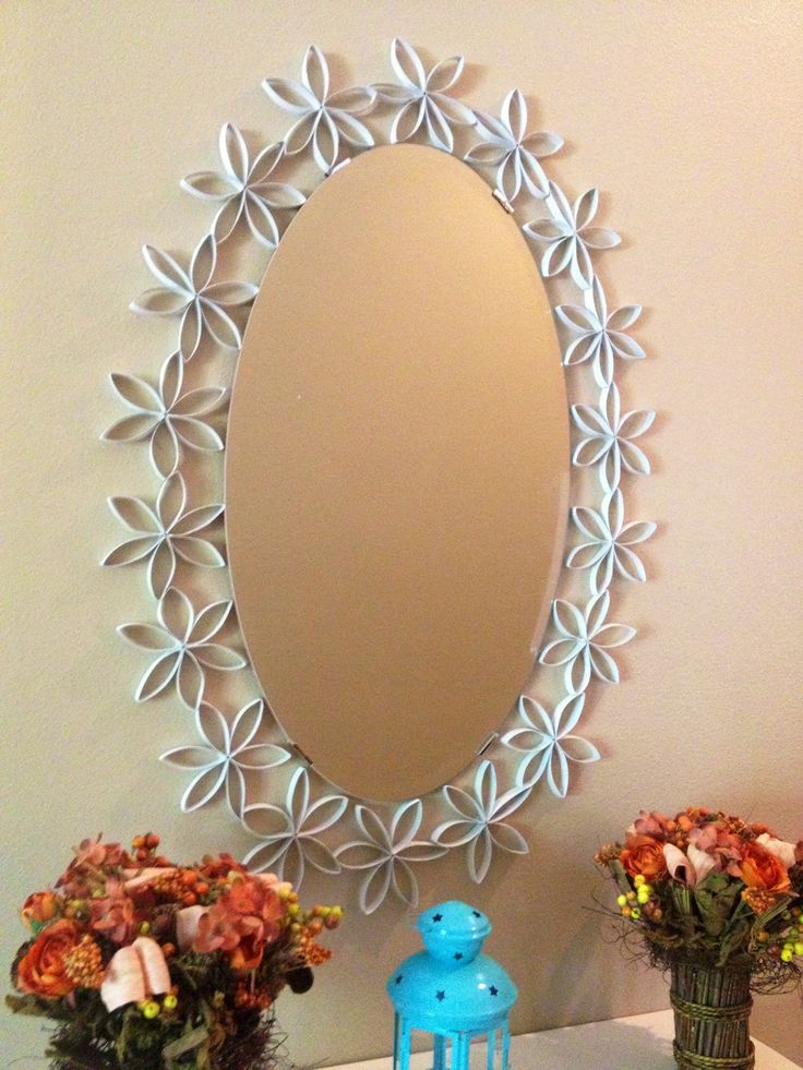 a mirror sitting on top of a table next to vases with flowers