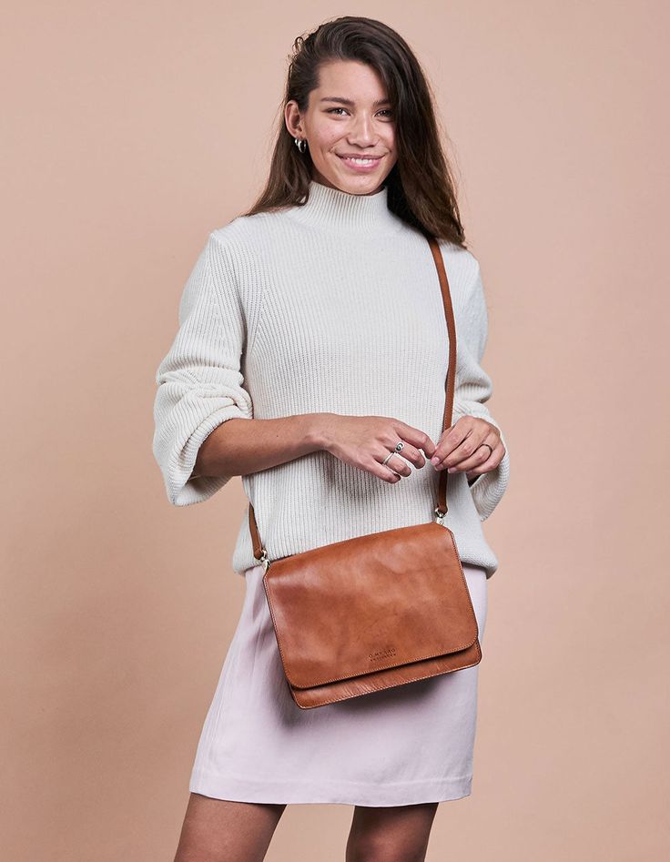 Our Audrey is a sleek and minimalist design that works well no matter the season or your outfit! The smooth leather satchel has an external front compartment and a canvas-lined interior that features a roomy compartment with a zipped side pocket for your belongings. Two open inside pockets make it easy to stow away smaller items. And we haven't got to the best bit yet - this bag comes with two straps! Feeling like switching up your look, while keeping it classy? Use the checkered strap and every Classic Leather Trim Crossbody Satchel, Classic Crossbody Satchel With Leather Trim, Timeless Shoulder Bag For Travel In Fall, Versatile Cognac Shoulder Bag For Business, Classic Leather Trim Crossbody Flap Bag, Classic Rectangular Saddle Bag With Leather Trim, Classic Saddle Bag With Leather Trim Satchel Shape, Classic Flap Shoulder Bag With Leather Trim, Chic Everyday Cognac Satchel