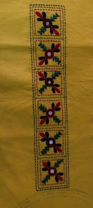 an embroidered yellow cloth with red, green and blue flowers on the border is shown