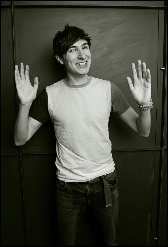 a man standing in front of a blackboard holding his hands up