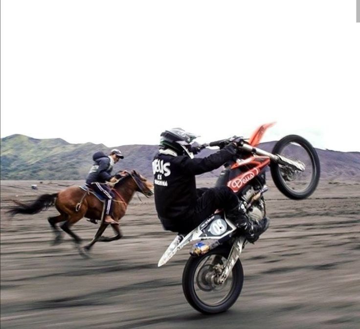 a man riding on the back of a dirt bike while being pulled by a horse