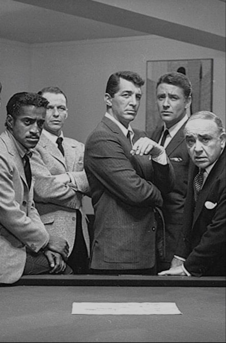 a group of men standing around a pool table