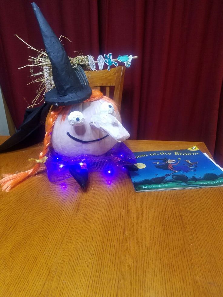 a stuffed animal wearing a witches hat sitting on top of a table next to a book