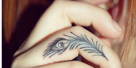 a woman with a feather tattoo on her left hand and an eye in the middle