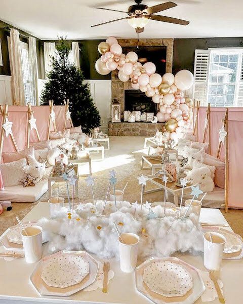 a table set up for a baby shower with balloons in the air and pink chairs