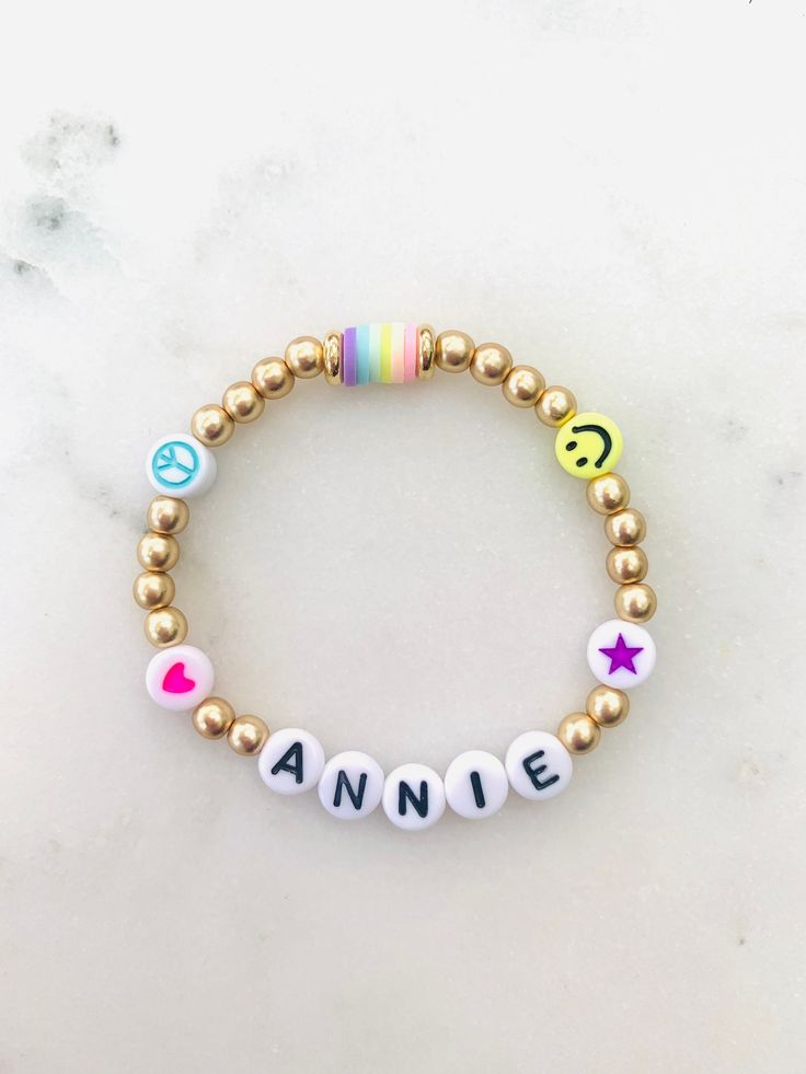 🌈 Colorful emoji beads with matte gold accents make this name bracelet one of the cutest. Can be made in adult or child sizes. Please note name/word and any color preference of the heart, star or peace sign in the personalization section. 🌈 Listing is for ONE bracelet.  🌈 Sizing length is as follows:  Women's small: 6.5 inches Women's medium: 7 inches Women's large: 7.5 inches Women's XL: 8 inches Children's 4-5 years old: 5.75 inches Children's 6-7 years old: 6 inches Children's 8-9 years old: 6.25 inches Children's 10-13 years old: 6-7 inches **Please measure wrist before ordering. Bracelets are stretchy but you do not want them to be super loose around your wrist.  🌈 All orders are FINAL SALE. These are custom bracelets made to order. PLEASE DOUBLE CHECK ALL SPELLING AND COLOR SELEC Trendy Customizable Name Bracelet, Playful Gold Beaded Bracelets For Everyday, Trendy Personalized Charm Bracelet For Birthday, Personalized Trendy Charm Bracelet For Birthday, Cute Name Bracelet With Round Beads For Everyday, Cute Everyday Name Bracelet With Round Beads, Playful Personalized Beaded Bracelets, Fun Letter Beads Name Bracelet For Birthday, Cute Gold Stretch Bracelet With Letter Beads