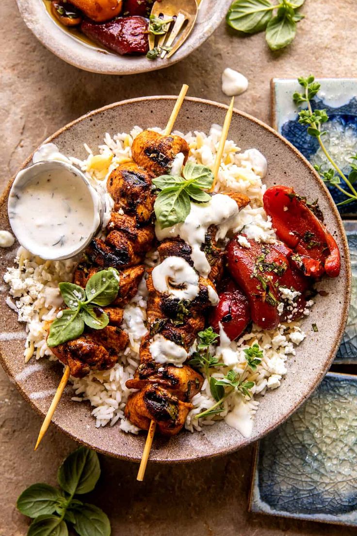 two plates filled with chicken and rice on top of a table next to bowls of vegetables