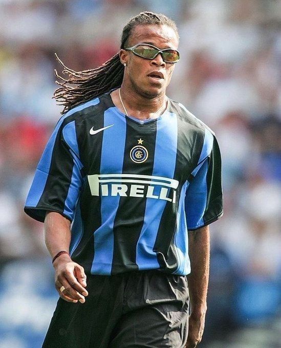 a man with dreadlocks and sunglasses is playing soccer in front of a crowd