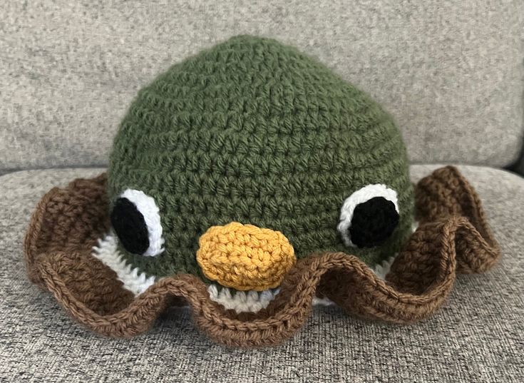 a green knitted hat with an octopus on it's face and eyes, sitting on a couch