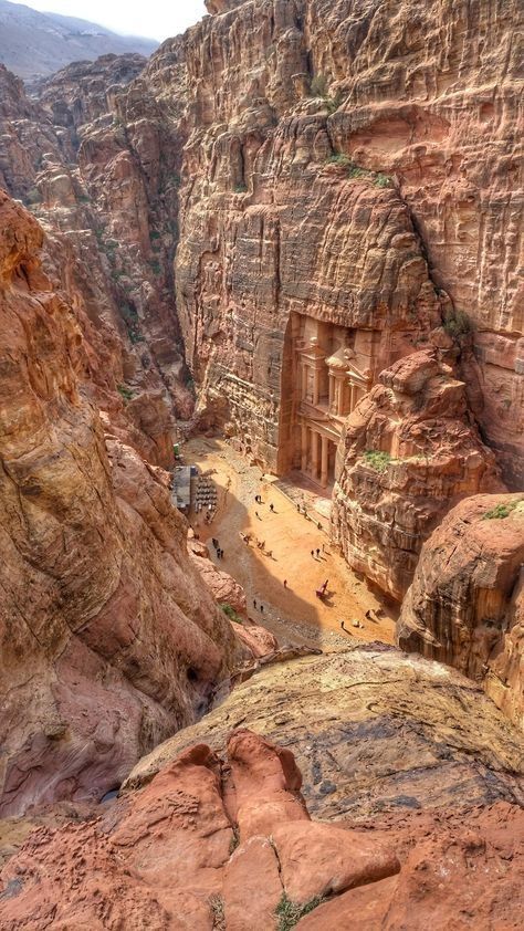 some people are standing in the middle of an area that looks like it is carved out of red rocks