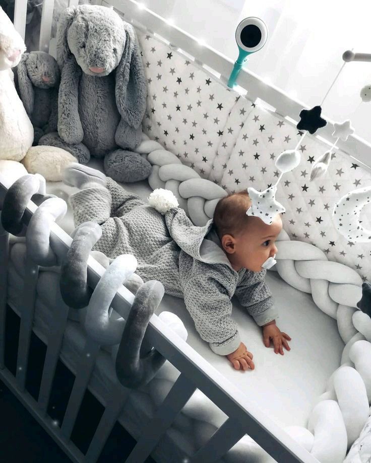 a baby laying in a crib surrounded by stuffed animals