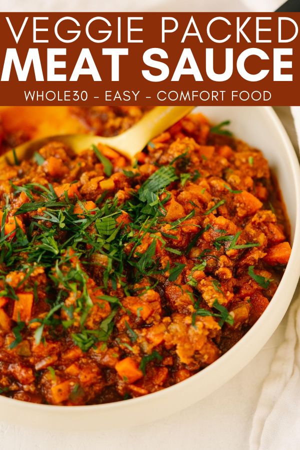 a white bowl filled with meat sauce and garnished with parsley on top