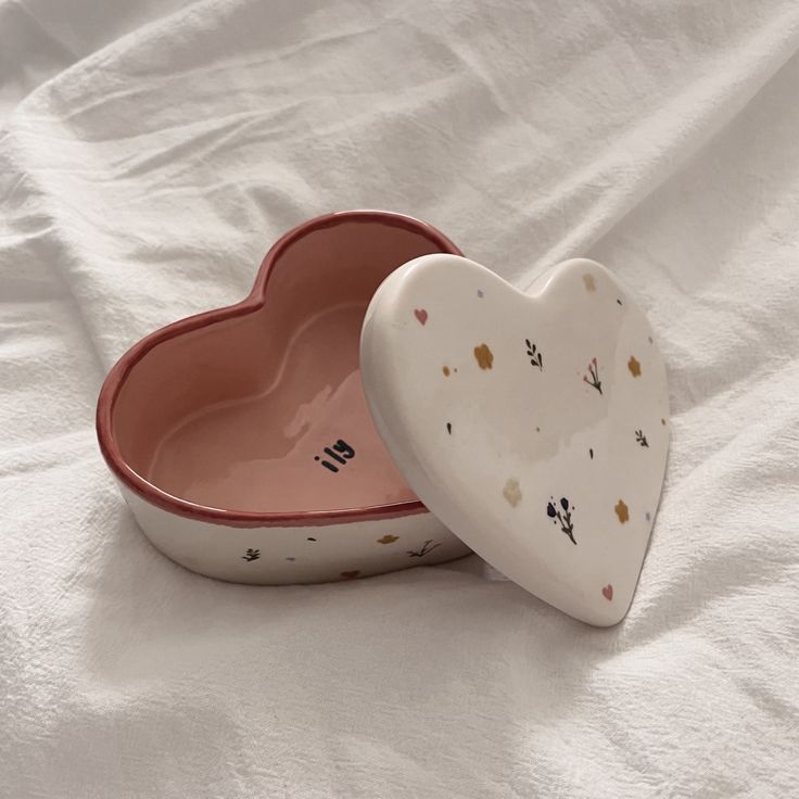 two heart shaped dishes sitting on top of a white sheet