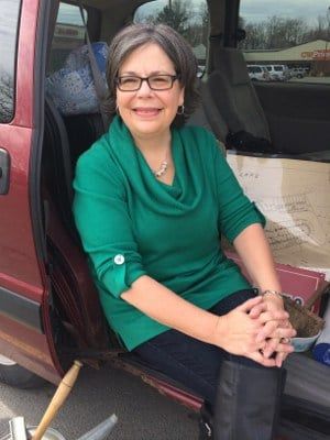 a woman sitting in the back of a van with her legs crossed and boots on