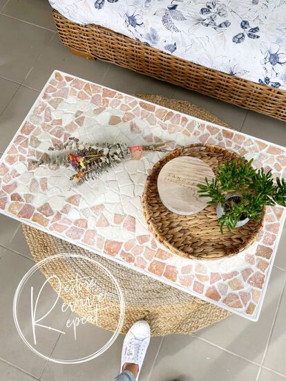 a wicker basket with plants on top of it next to a bed and table