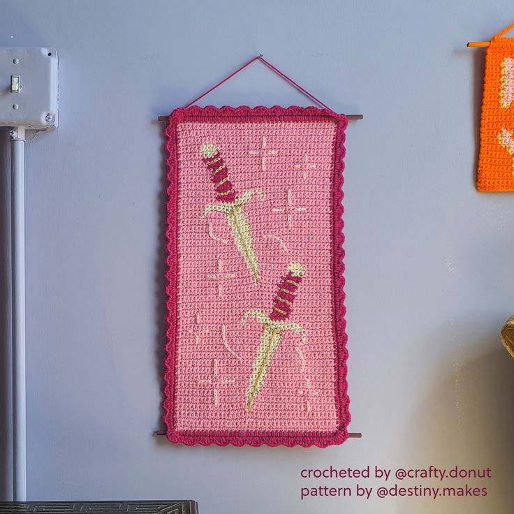 a pink wall hanging on the side of a white wall