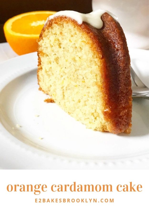 a slice of cake on a white plate with an orange in the backgroun