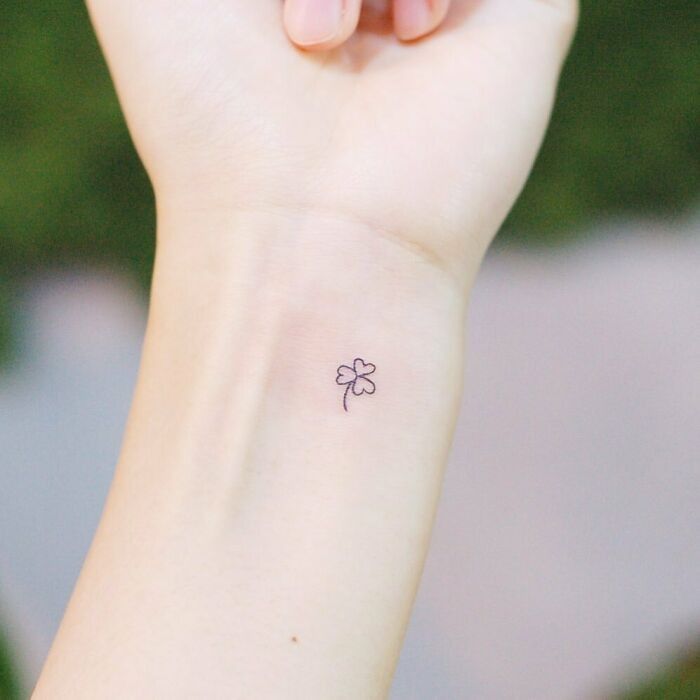 a small four leaf clover tattoo on the wrist