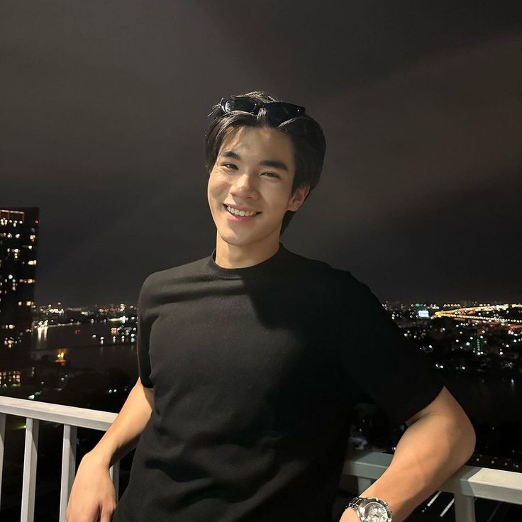 a man standing on top of a balcony next to a night time cityscape