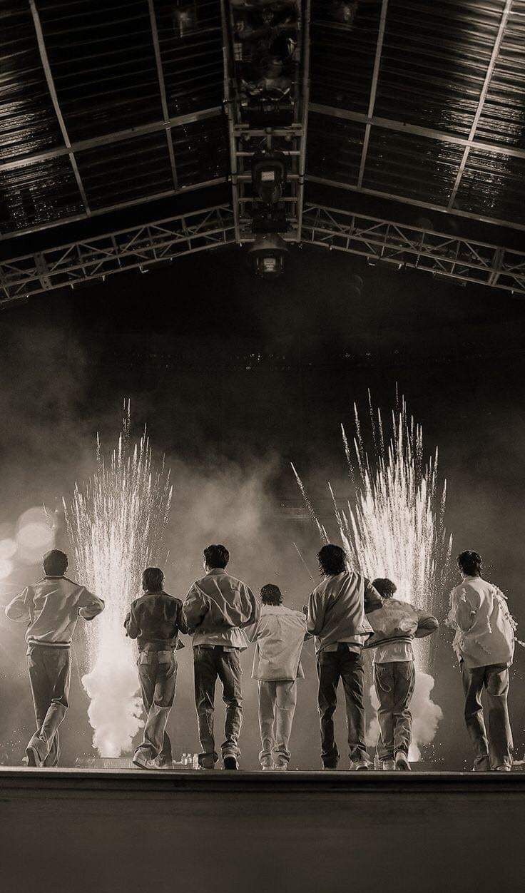 a group of people standing on top of a stage with fireworks in the air behind them