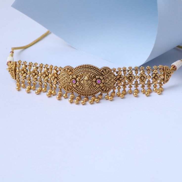 Description Inspired from the shimmering Indian gold jewelry. This Collection is designed to highlight the fine Indian craftsmanship. It is crafted in gold-plated 925 silver with intricate textures and tones. Modern designs adorn you with timeless floral patterns. This jewelry is perfect for wedding and festival events. Meet your new silver choker set from the Swara family. Designed with floral intricates and unique textures, this bold choker features pink stones in gold tone finish. Very unique Antique Gold Jewelry With Intricate Design For Diwali, Antique Gold Intricate Jewelry For Diwali, Antique Gold Necklace With Intricate Design For Weddings, Ornate Antique Gold Festive Jewelry, Festive Ornate Antique Gold Jewelry, Elegant Design Temple Necklace For Festive Season, Kundan Filigree Yellow Gold Jewelry, Yellow Gold Kundan Filigree Jewelry, Ceremonial Yellow Gold Temple Bridal Necklace