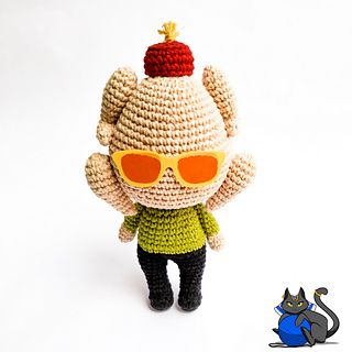 a crocheted doll with sunglasses and a cat sitting next to it on a white surface