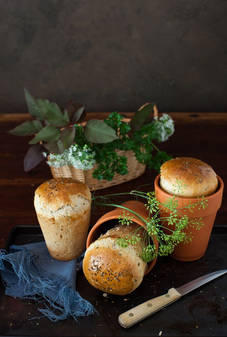 breads and flowers on a tray next to a potted plant with a knife