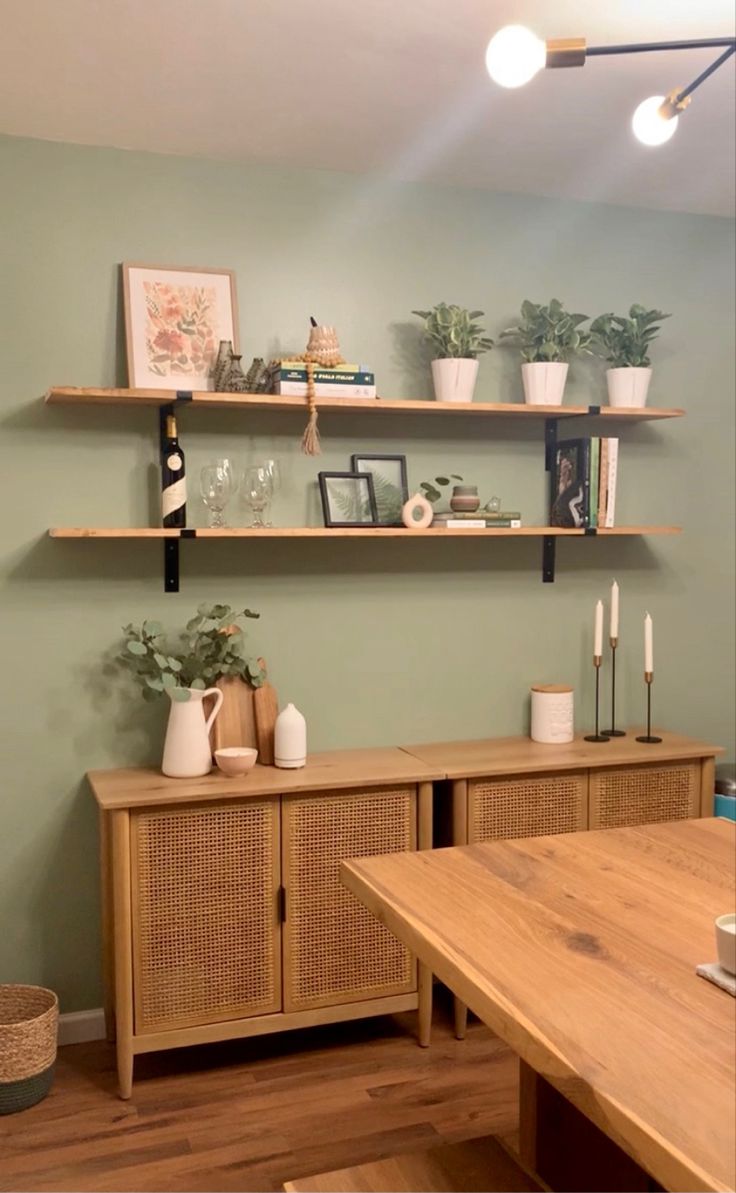 a living room with shelves and plants on the wall next to a wooden dining table