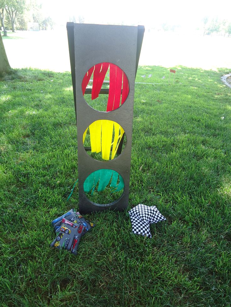 a traffic light sitting on top of a lush green field next to a trash can