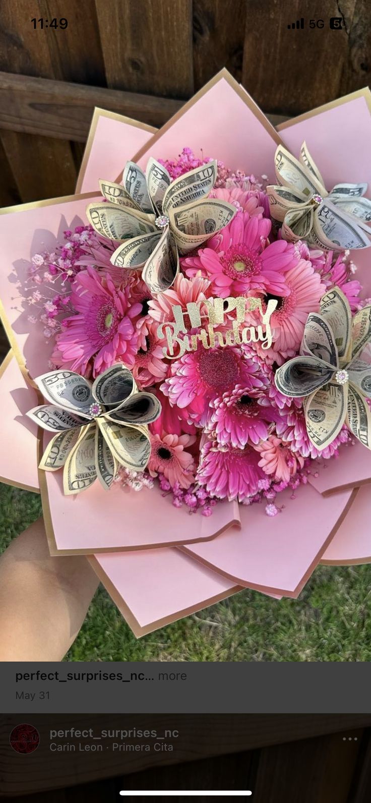 a pink flower bouquet with money in the center and happy birthday written on it's side