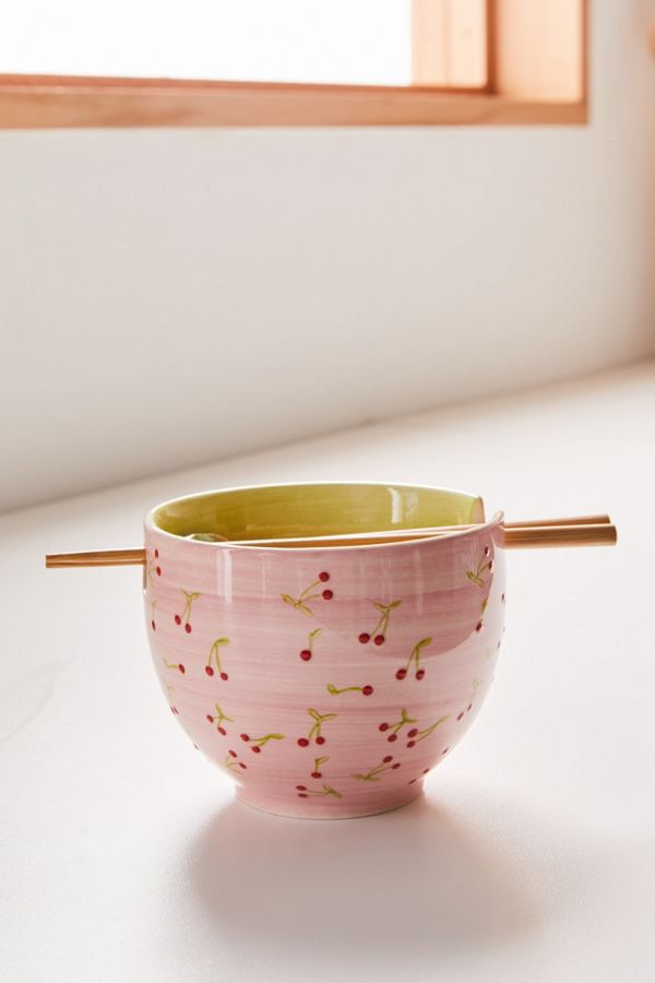 a pink and yellow bowl sitting on top of a white counter next to a window