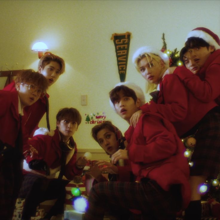 a group of young men standing next to each other in front of a christmas tree