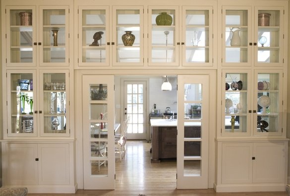 an open kitchen with white cabinets and glass doors that lead to the dining room area