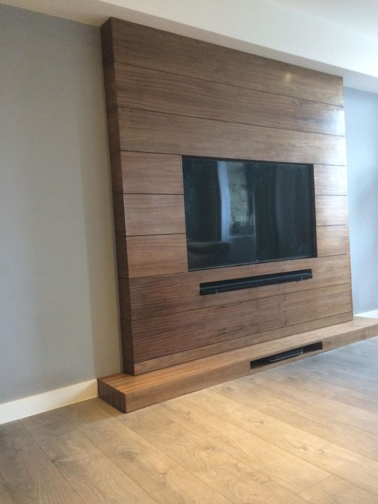 a flat screen tv mounted to the side of a wall in a living room with hardwood flooring