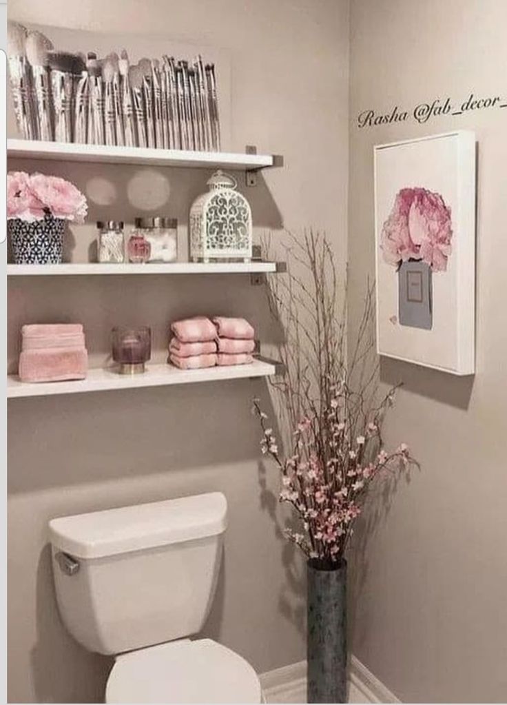 a white toilet sitting in a bathroom next to a shelf filled with pink towels and other items